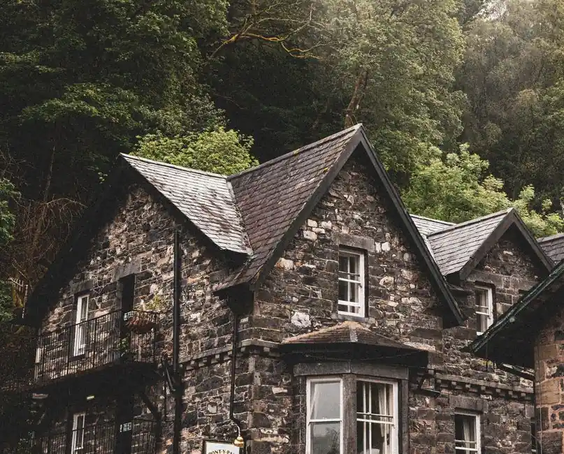 Rustic stone cottage surrounded by lush greenery in Betws-y-Coed, Wales.